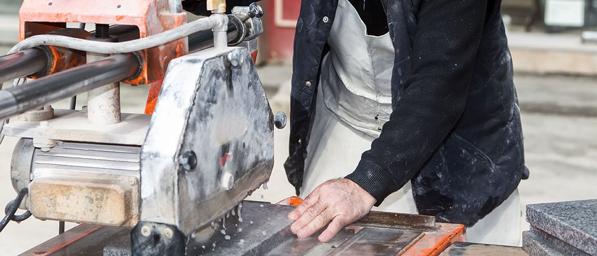 Worker cutting marble using a wet method to minimize silica exposure