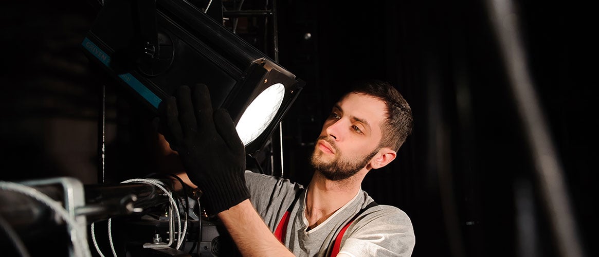 Live event worker installing a spotlight before a performance.