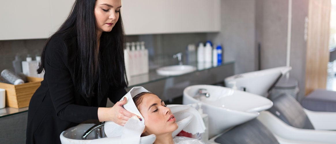 Hairdresser shampooing client at salon at adjustable shampoo bowl