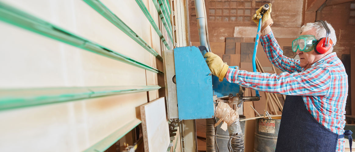 Mill worker using eye and hearing protection while operating vertical milling saw