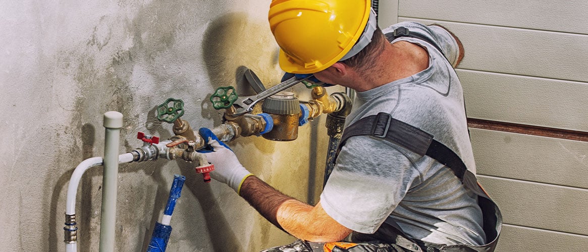 Plumber using an adjustable wrench to work on pipes at a jobsite.