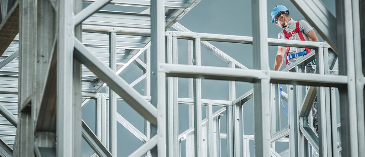 Construction worker with fall protection standing on a skeleton steel structure.