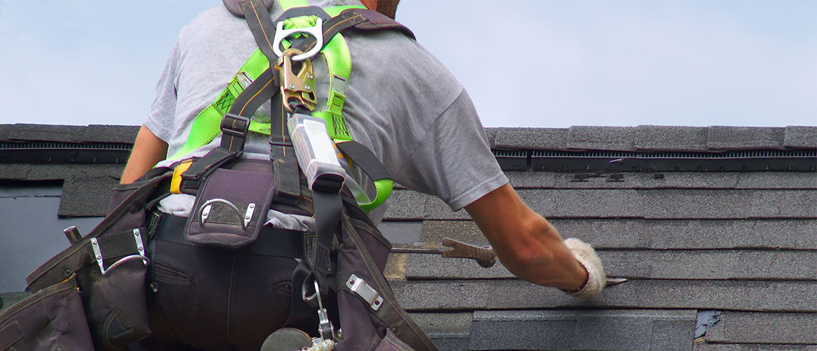 Worker installing a roof while wearing fall protection