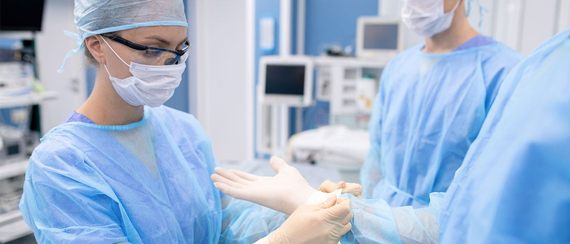 Medical professional helping coworker put on gloves