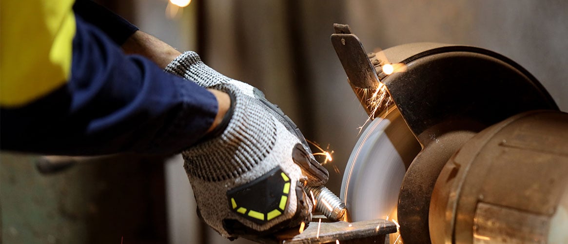 Manufacturing employee wearing gloves while using a grinder