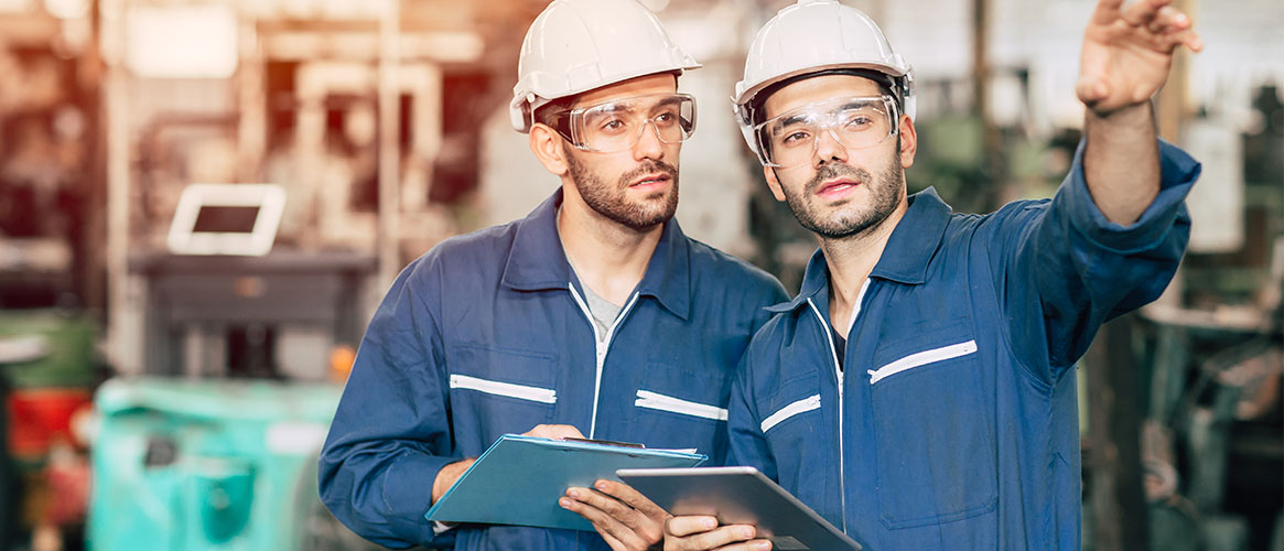 Two workers discussing and making notes of their findings during a safety audit.