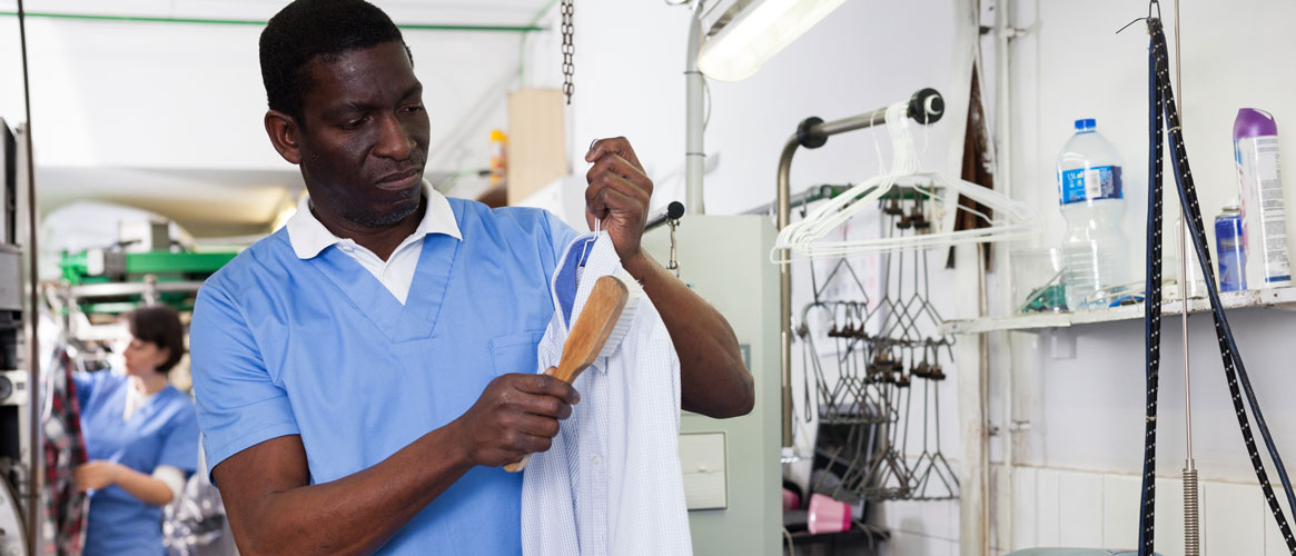 Dry clean worker holding shirt up to inspect while maintaining healthy ergonomic posture