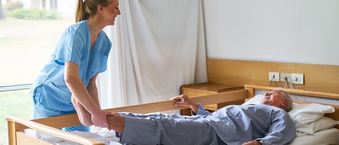Nurse providing care to an elderly patient that is lying in bed