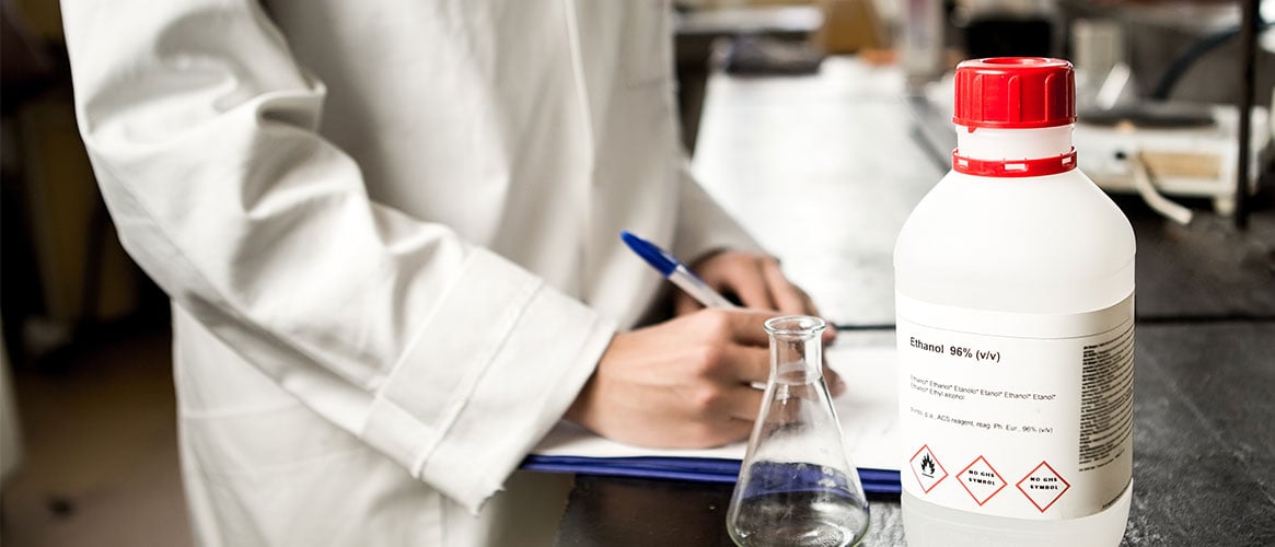 Employee taking notes on chemical, which shows GHS pictogram on its hazards