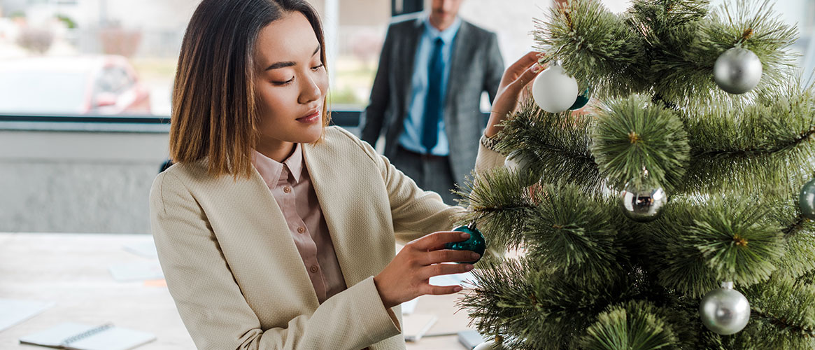 a woman decorating a holiday tree