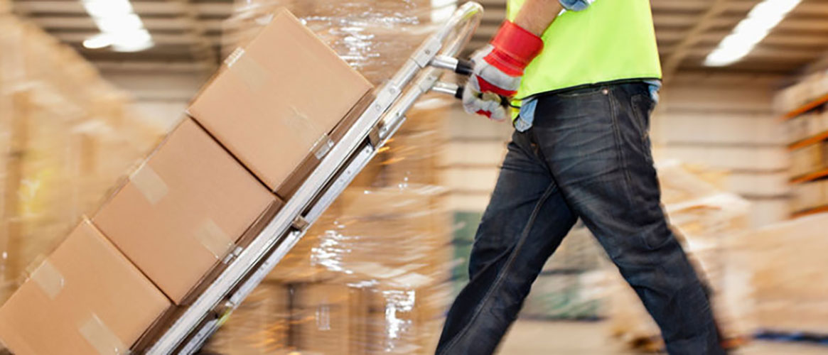 Warehouse worker safely moving heavy boxes with handtruck