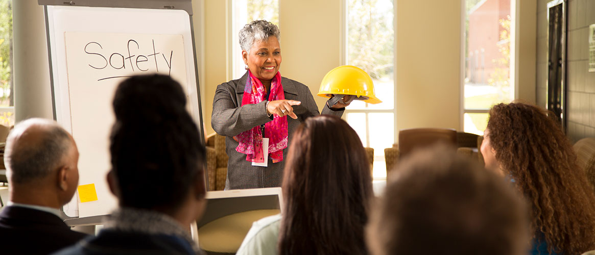 Safety instructor shows protective equipment to class of staff